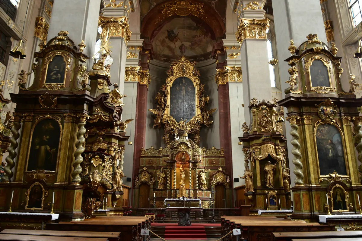 The high altar and two side altars of St Giles' Church, with gilded frames, twisted columns and painted altarpieces.