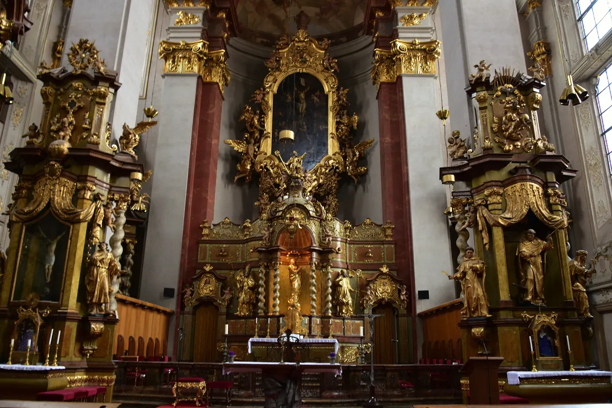The high altar of St Giles' Church with its gilded frame and painted altarpiece, flanked by side altars with carved figures.