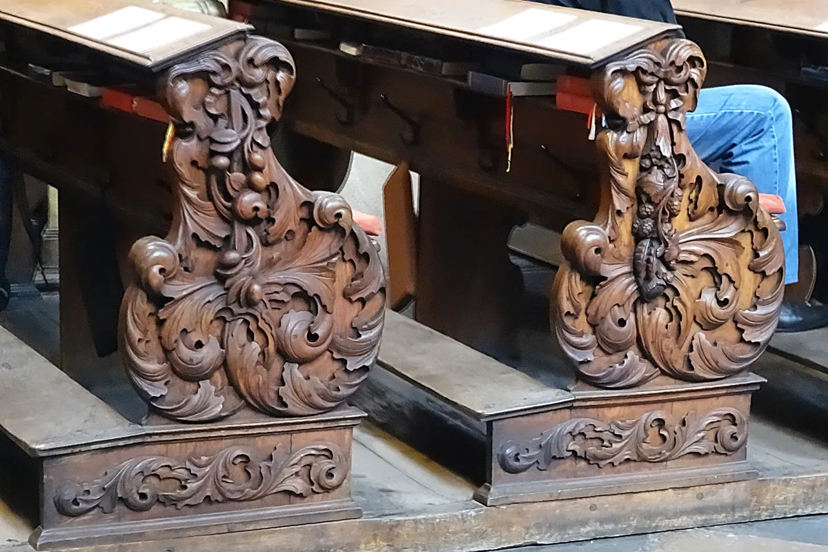 Two carved wooden pew ends with deep foliage scrolls in the nave of St Giles' Church.
